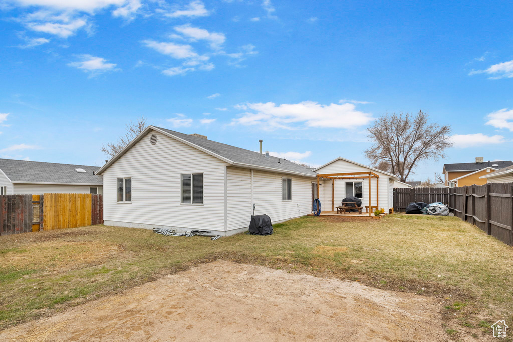 Back of property with a fenced backyard and a lawn