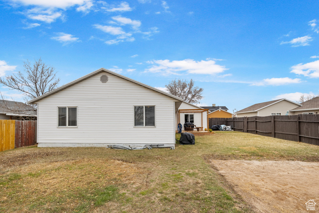 Rear view of property with a fenced backyard, a patio, and a yard