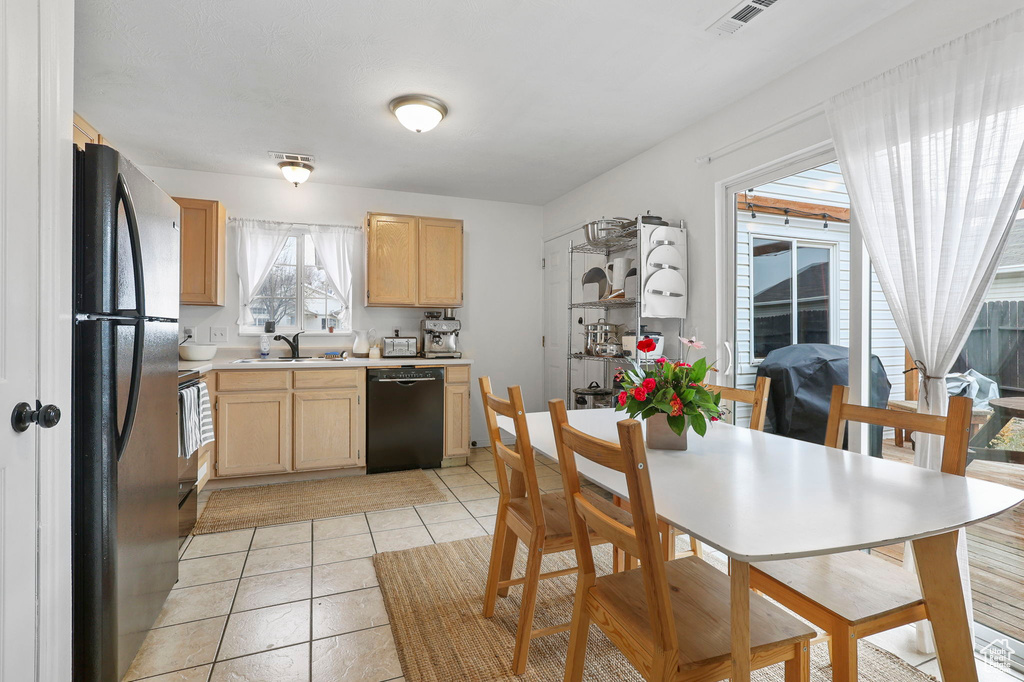 Kitchen with visible vents, light countertops, light brown cabinetry, black appliances, and a sink