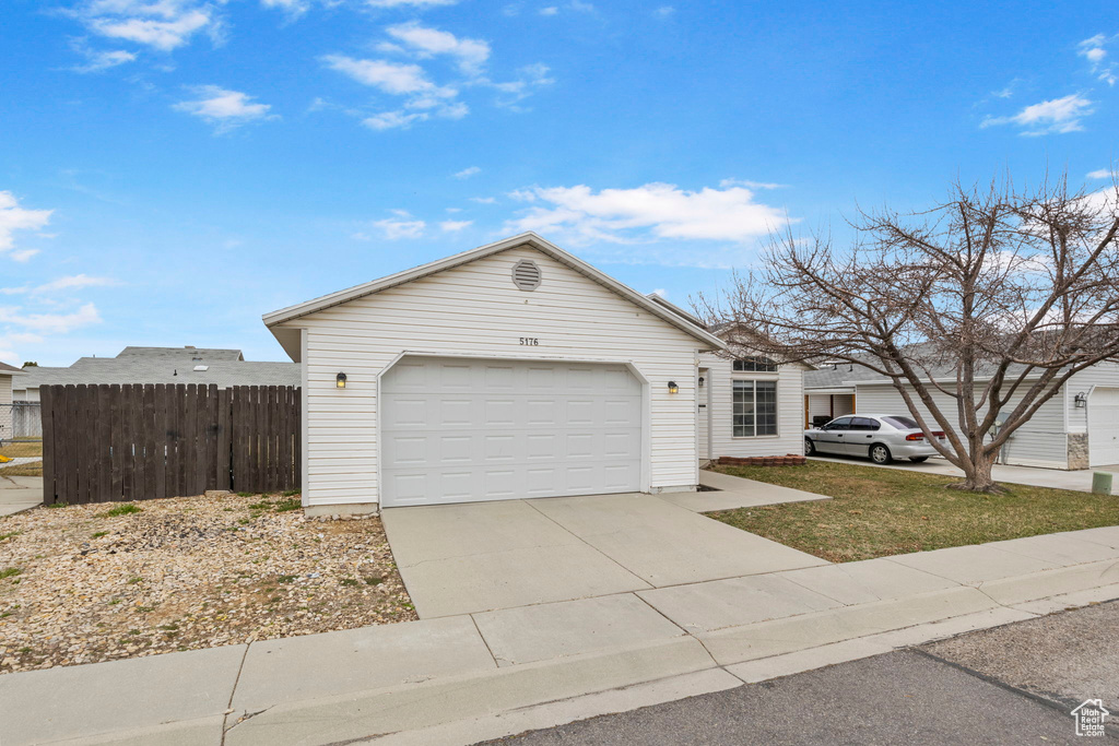 View of front of house with driveway, a garage, and fence