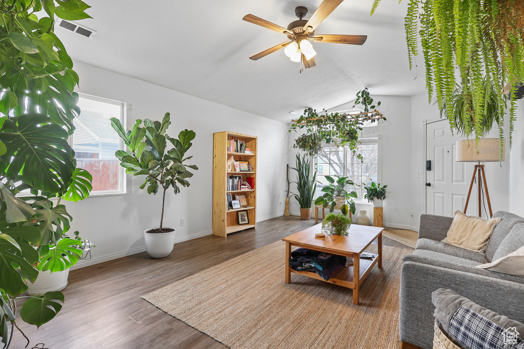 Living room with ceiling fan, wood finished floors, visible vents, baseboards, and vaulted ceiling