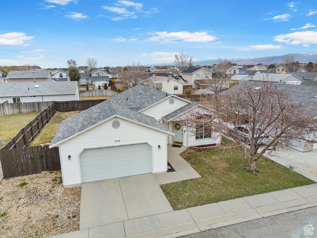 Traditional home featuring driveway, an attached garage, a residential view, and a front lawn