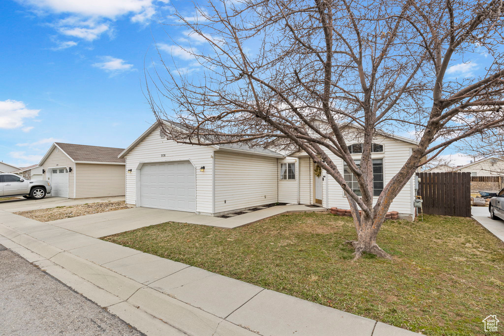 View of front of home with an attached garage, a shingled roof, fence, concrete driveway, and a front lawn