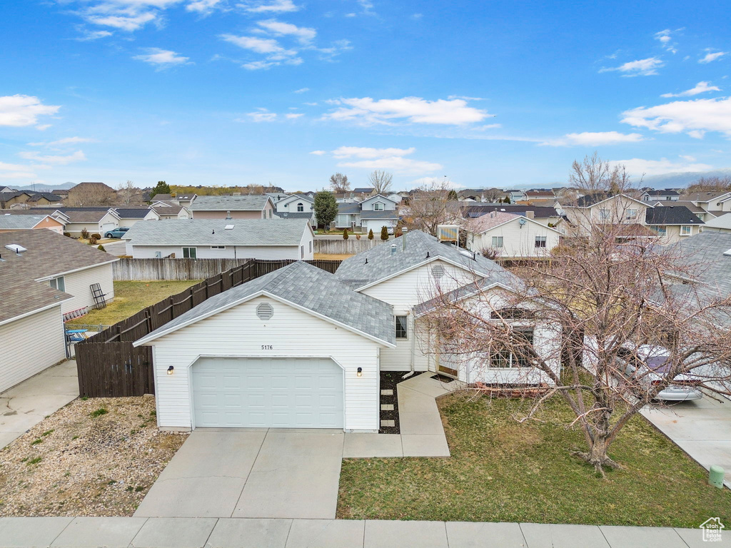 View of front of home featuring a garage, a residential view, fence, and concrete driveway