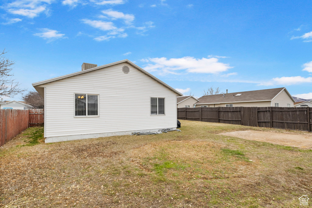 Rear view of property with a fenced backyard and a lawn