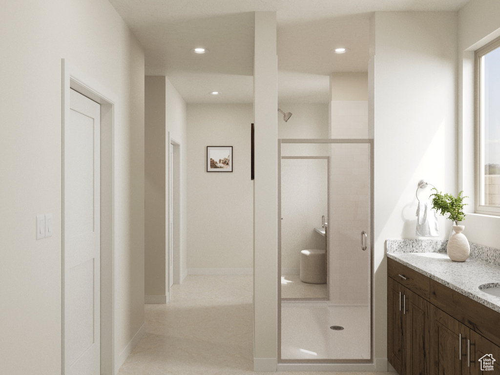 Full bath with baseboards, a stall shower, vanity, and recessed lighting