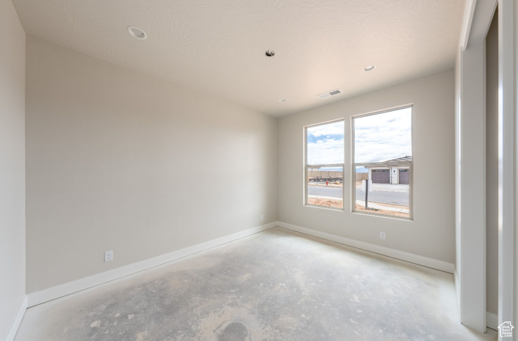 Unfurnished room featuring unfinished concrete flooring, baseboards, and recessed lighting