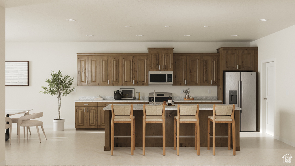 Kitchen featuring a breakfast bar, stainless steel appliances, recessed lighting, light countertops, and an island with sink