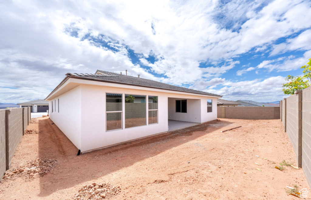Back of property with a fenced backyard, stucco siding, and a patio