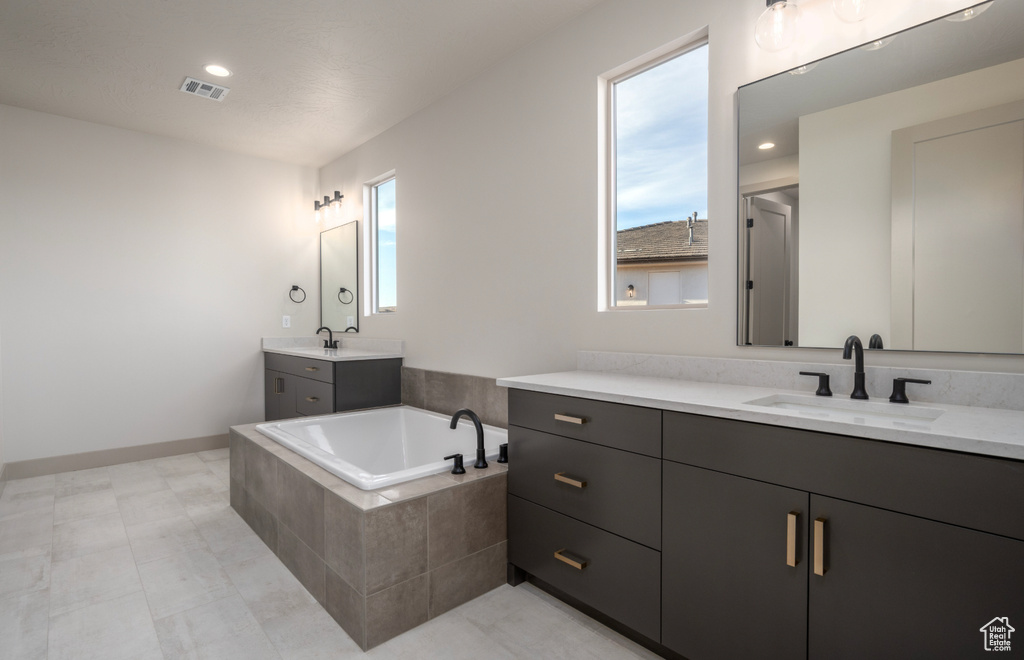 Full bathroom featuring a sink, two vanities, a bath, and visible vents