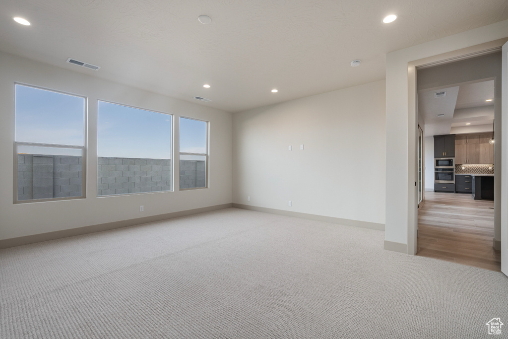 Empty room with light colored carpet, visible vents, baseboards, and recessed lighting