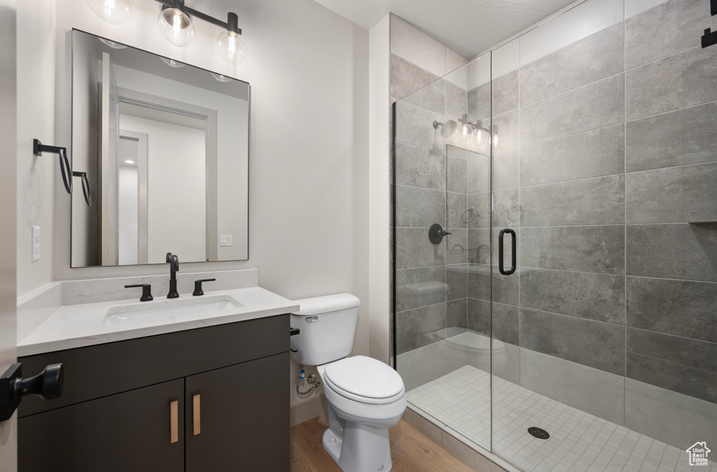 Full bathroom with a stall shower, vanity, toilet, and wood finished floors