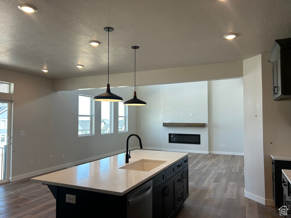 Kitchen featuring a sink, dishwasher, a textured ceiling, dark wood-style flooring, and healthy amount of natural light