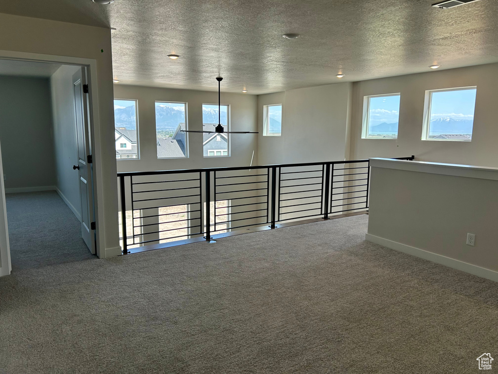 Unfurnished room featuring carpet flooring, a textured ceiling, baseboards, and plenty of natural light
