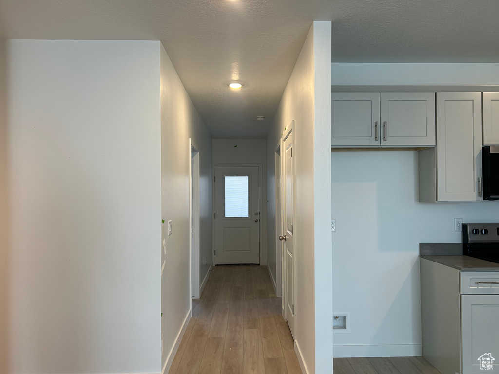 Hall with light wood-style flooring and baseboards