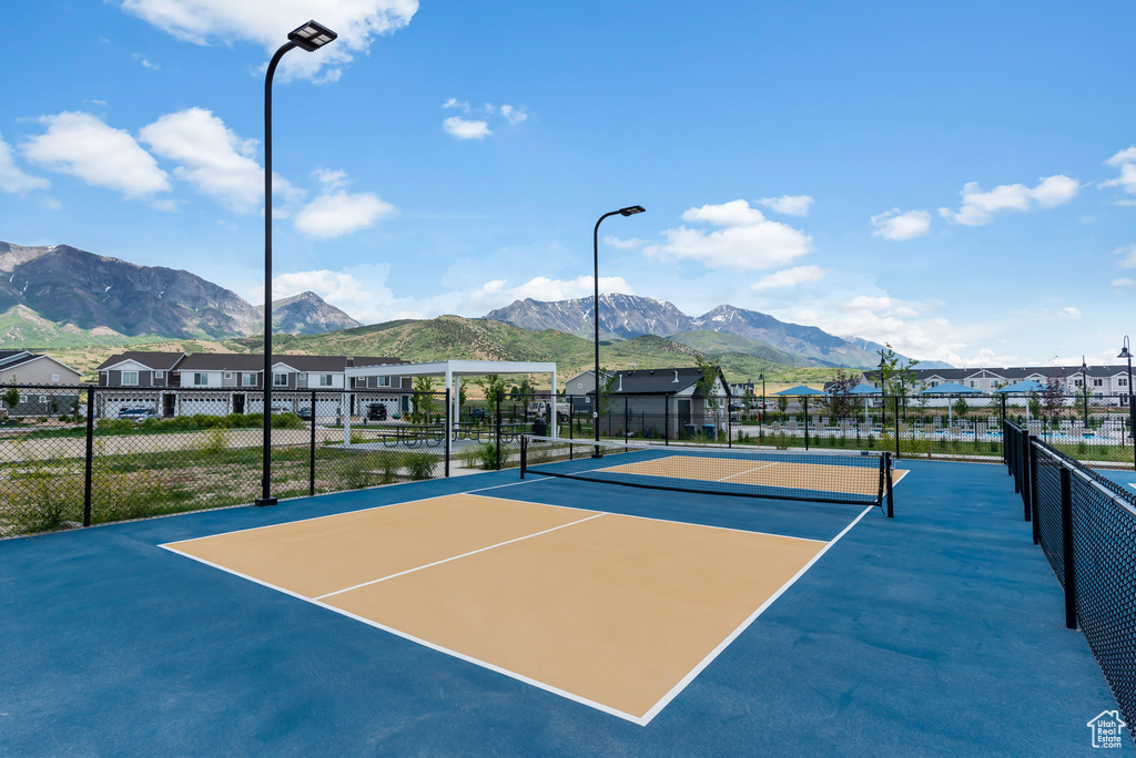 View of tennis court featuring a mountain view, community basketball court, a residential view, and fence