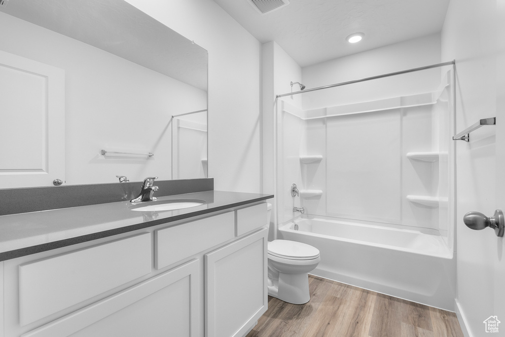 Full bathroom with toilet, wood finished floors, visible vents, vanity, and bathing tub / shower combination
