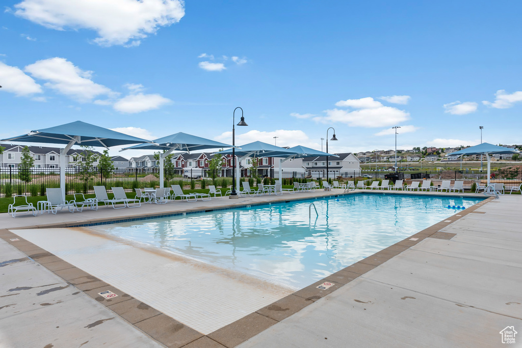 Community pool with a residential view, fence, and a patio