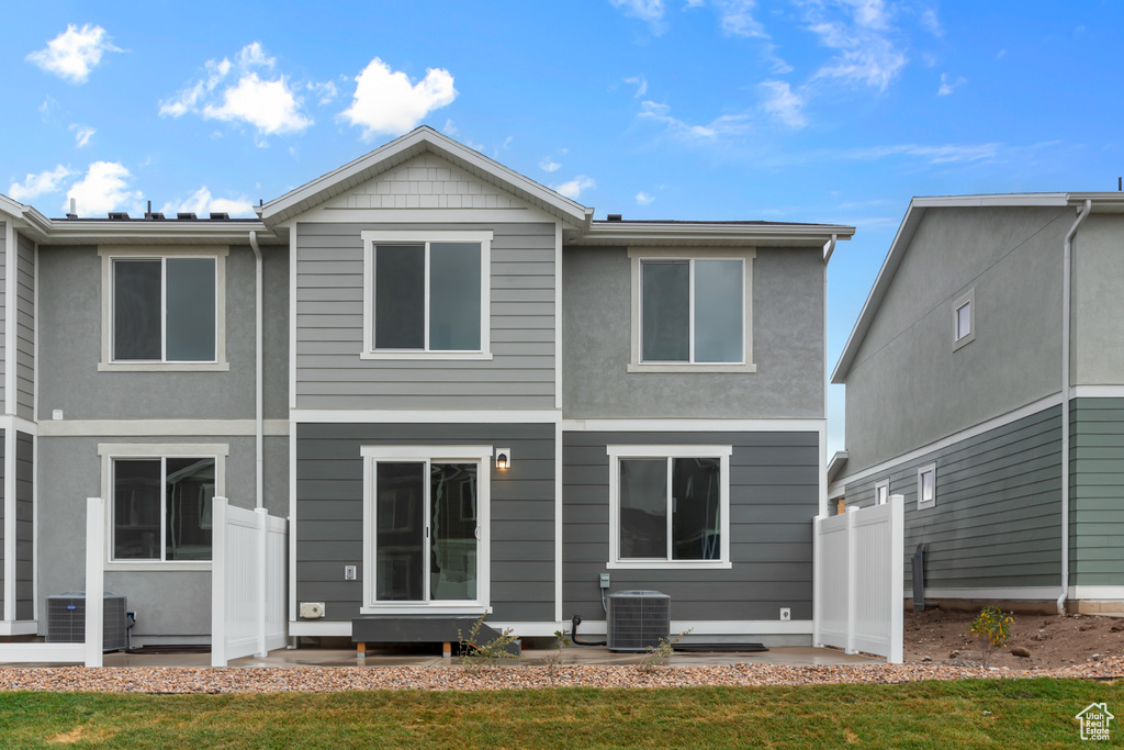 Back of house with fence, a lawn, central AC, and stucco siding