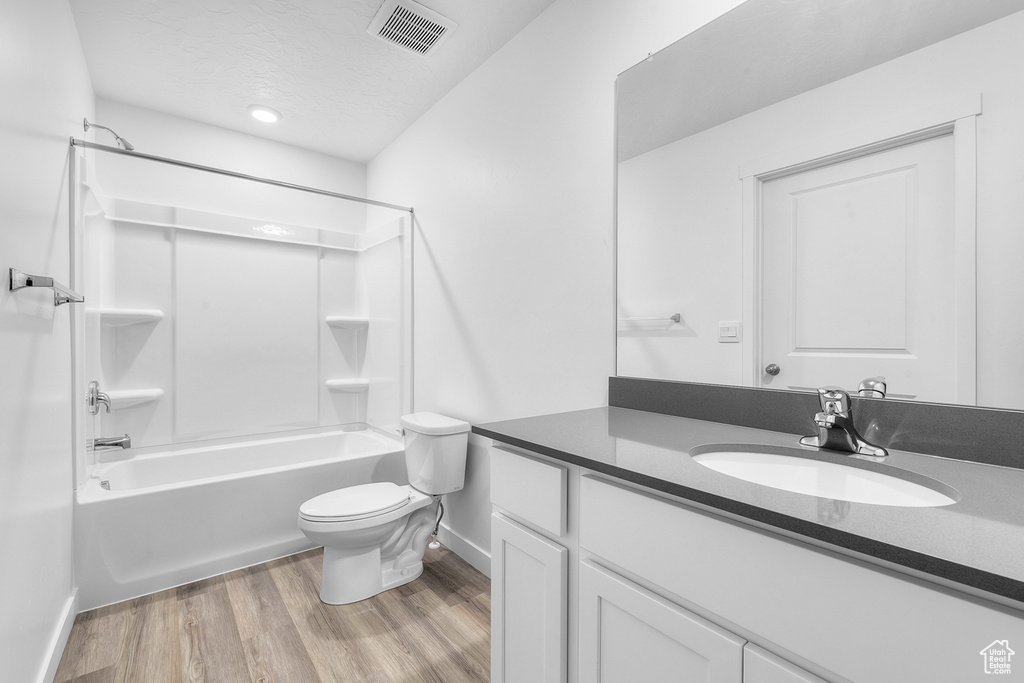 Bathroom featuring visible vents, toilet, shower / tub combination, wood finished floors, and vanity
