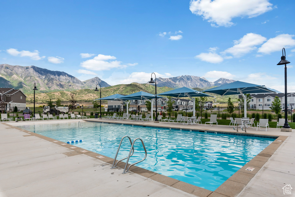 Community pool featuring a patio area, a residential view, fence, and a mountain view