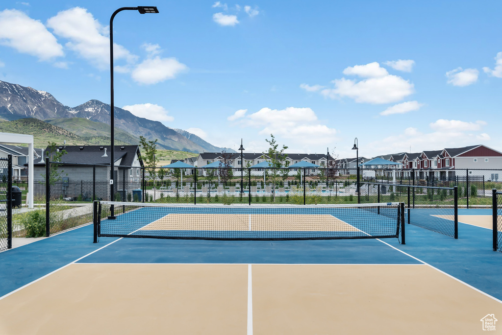 View of tennis court with a residential view, fence, and a mountain view