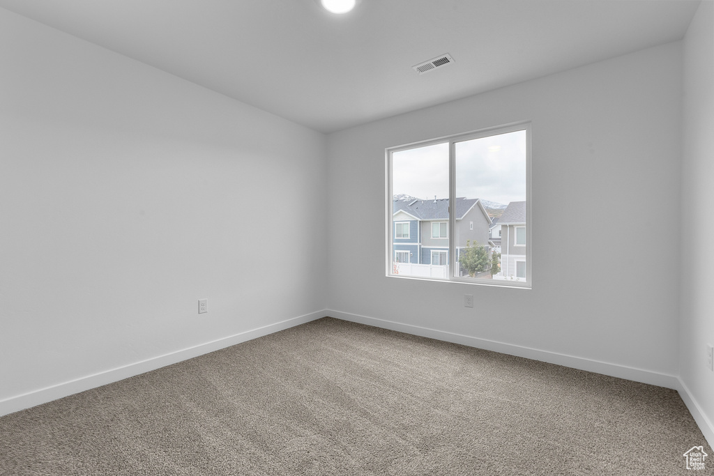 Carpeted spare room featuring visible vents and baseboards