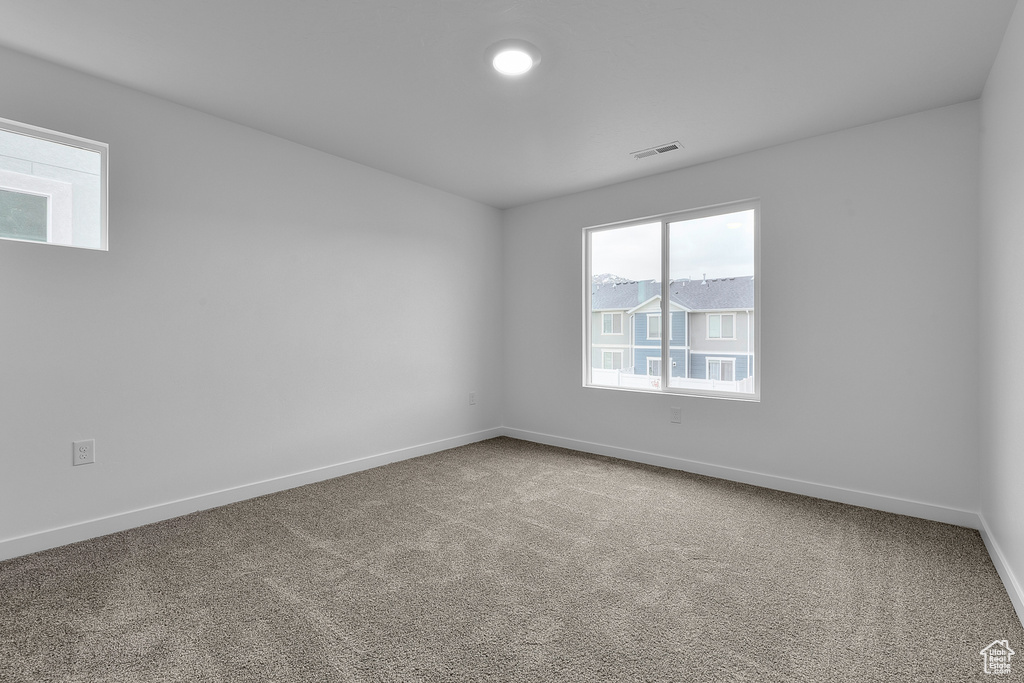 Empty room with carpet, visible vents, and baseboards