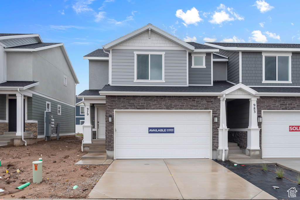 View of front of property with a garage, concrete driveway, roof with shingles, and stone siding