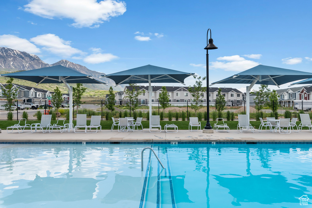 Community pool featuring a residential view, a patio area, fence, and a mountain view
