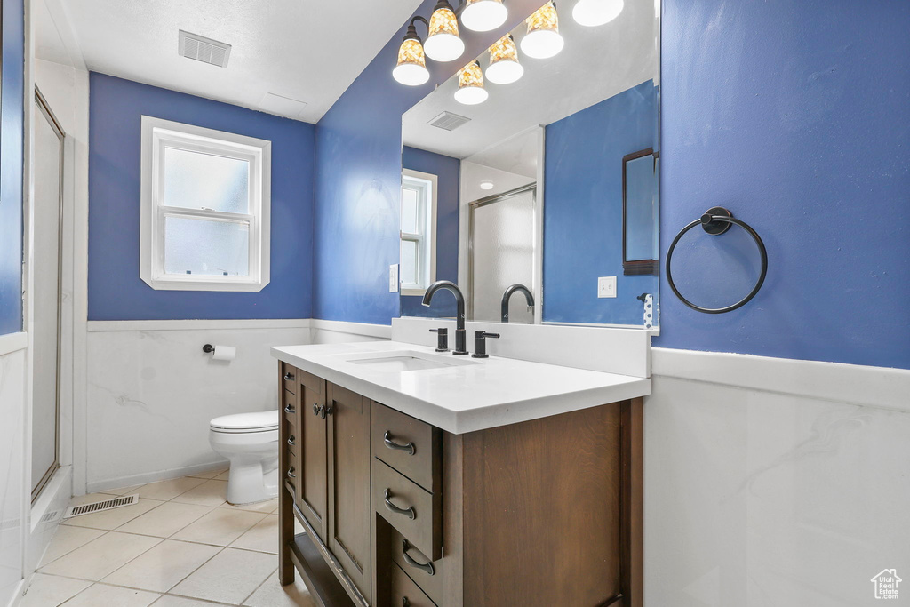 Bathroom with a wainscoted wall, a shower stall, visible vents, and tile patterned floors