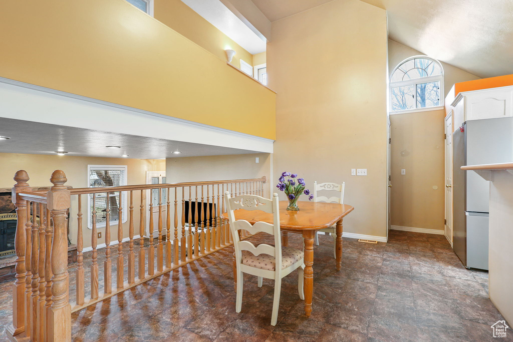 Dining room featuring high vaulted ceiling, stone finish floor, and baseboards