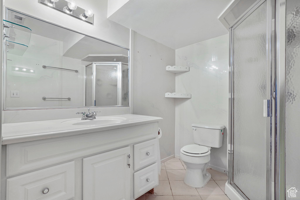 Bathroom with baseboards, toilet, tile patterned floors, vanity, and a shower stall