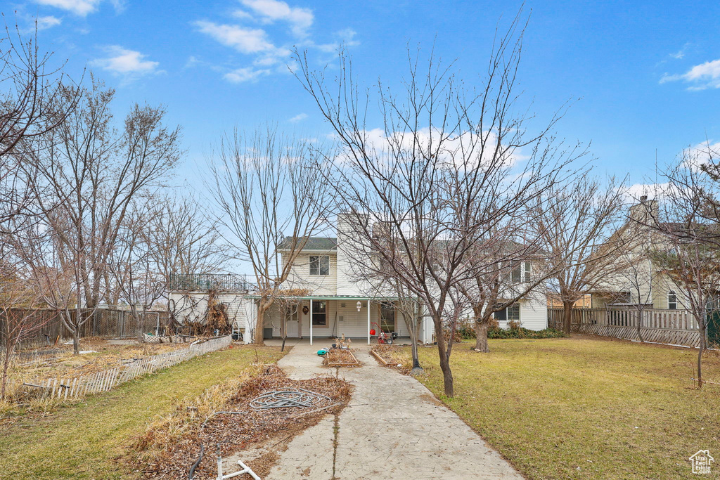 View of front facade featuring fence private yard, covered porch, driveway, and a front lawn