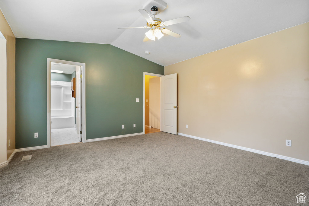 Interior space with lofted ceiling, ceiling fan, carpet, and baseboards