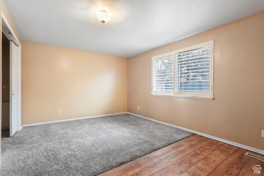 Unfurnished room featuring wood finished floors, visible vents, and baseboards