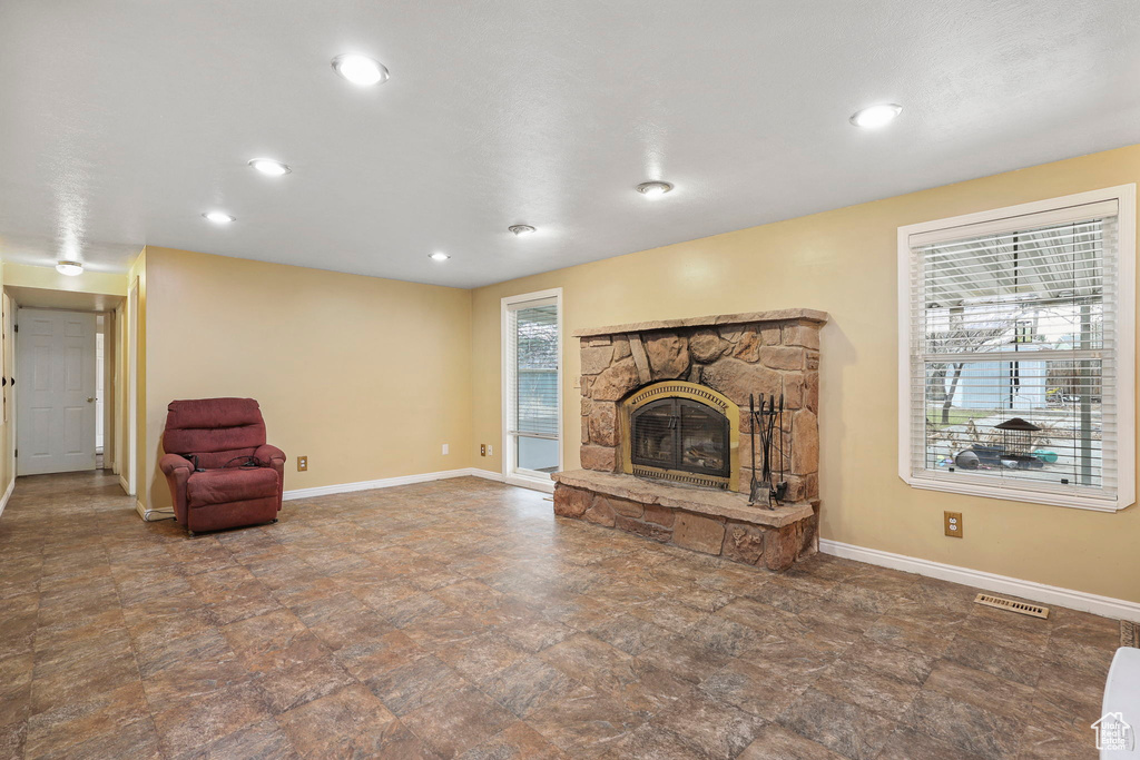 Unfurnished living room with recessed lighting, baseboards, visible vents, and a stone fireplace