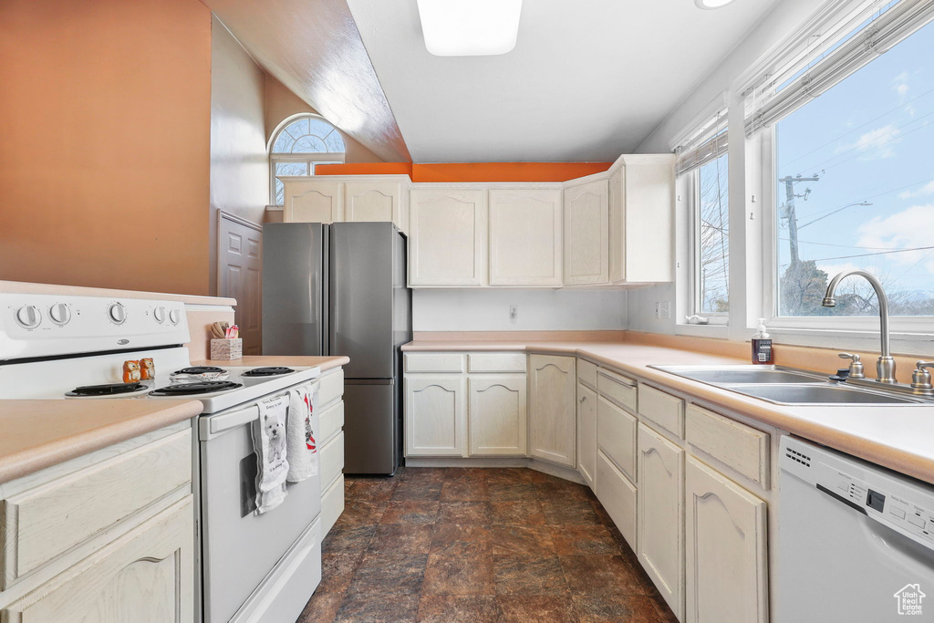 Kitchen with white appliances, a sink, white cabinetry, light countertops, and stone finish floor