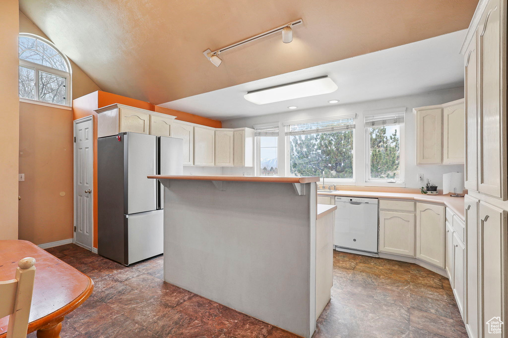 Kitchen with light countertops, a wealth of natural light, white dishwasher, and freestanding refrigerator