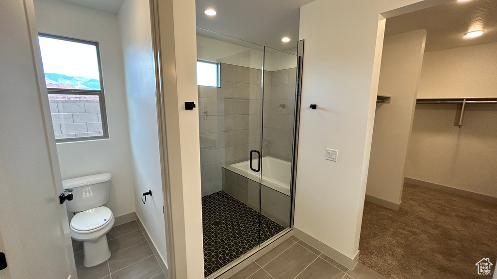 Bathroom featuring toilet, baseboards, plenty of natural light, and a stall shower