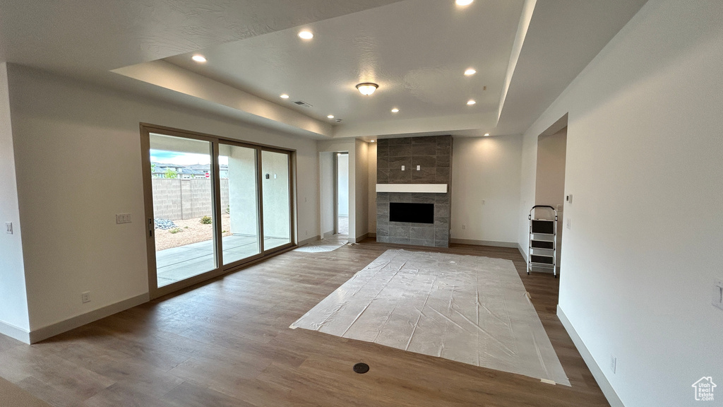 Unfurnished living room featuring baseboards, recessed lighting, a raised ceiling, and wood finished floors