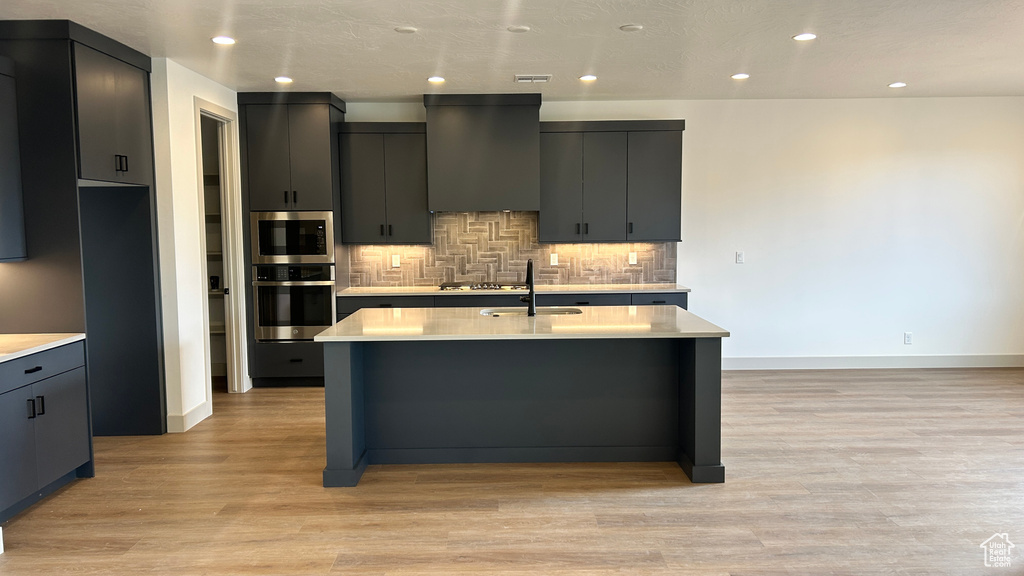 Kitchen featuring light countertops, stainless steel appliances, and light wood finished floors