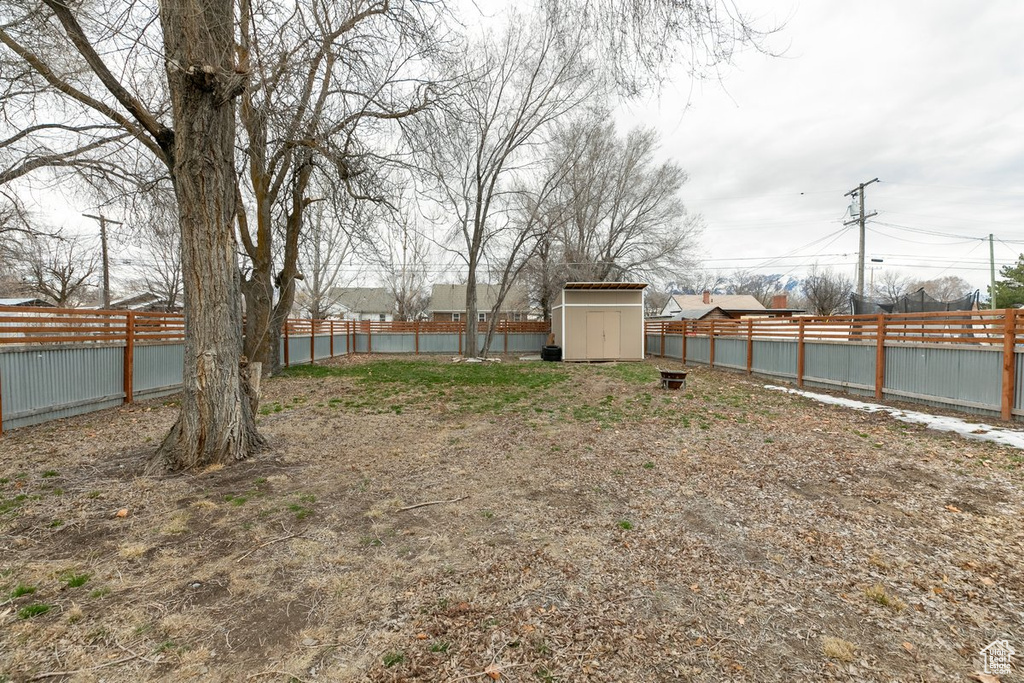 View of yard featuring a storage unit, an outdoor structure, and a fenced backyard