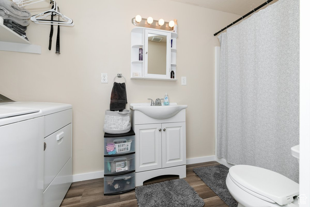 Bathroom with toilet, washer / clothes dryer, wood finished floors, and vanity