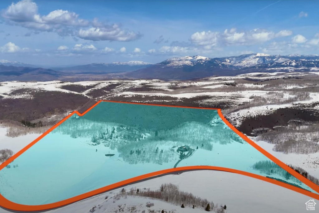 Snowy aerial view with a mountain view and property boundaries highlighted
