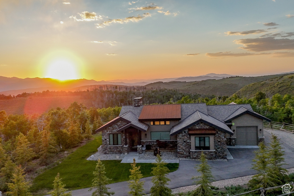 View of front of house with stone siding, a mountain view, a chimney, and dirt driveway