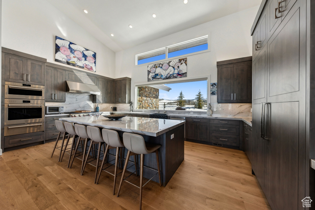 Kitchen with a high ceiling, stainless steel appliances, tasteful backsplash, a center island, and a breakfast bar