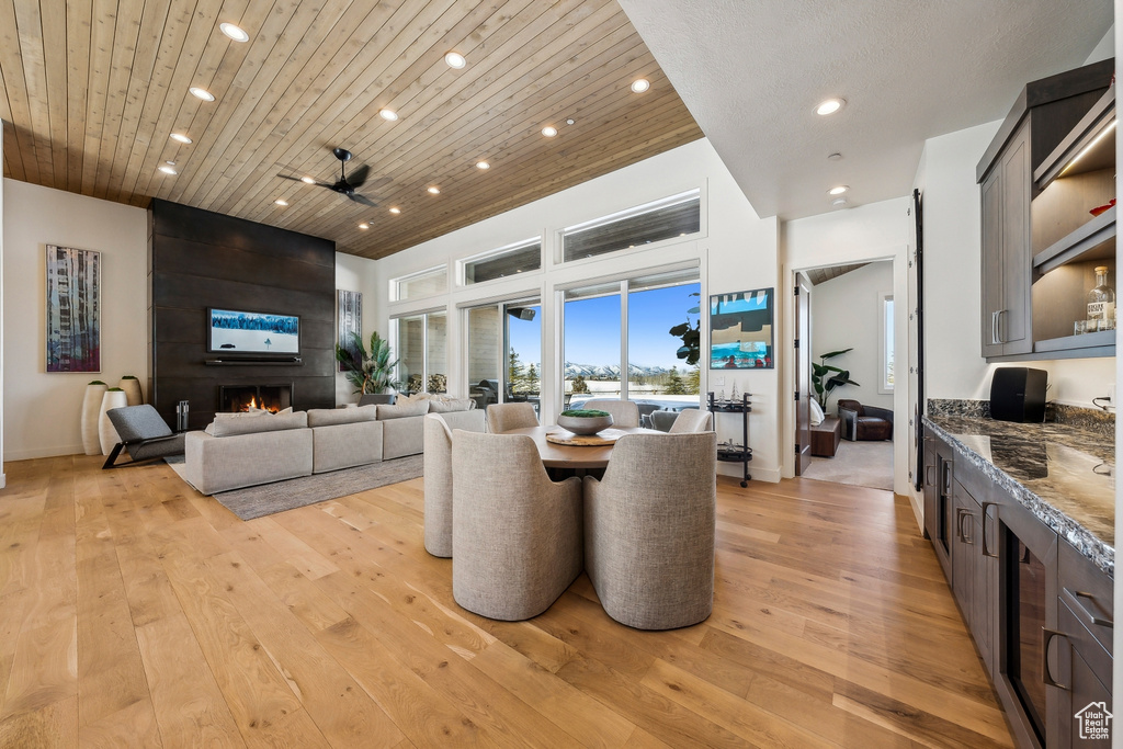 Dining room with recessed lighting, light wood-type flooring, wooden ceiling, a large fireplace, and ceiling fan