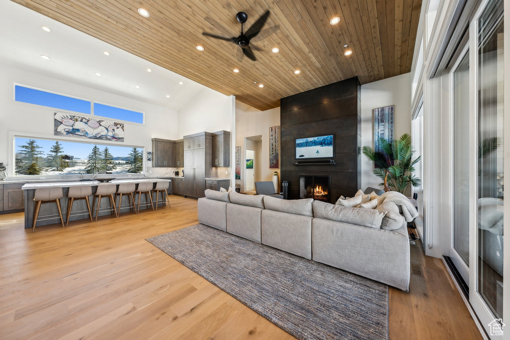 Living room with recessed lighting, a fireplace, a ceiling fan, light wood-style floors, and high vaulted ceiling