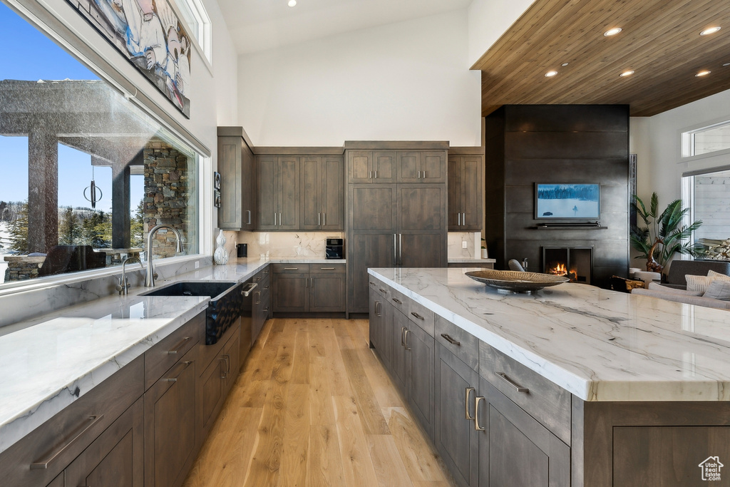 Kitchen with recessed lighting, a high ceiling, light wood finished floors, a fireplace, and light stone countertops